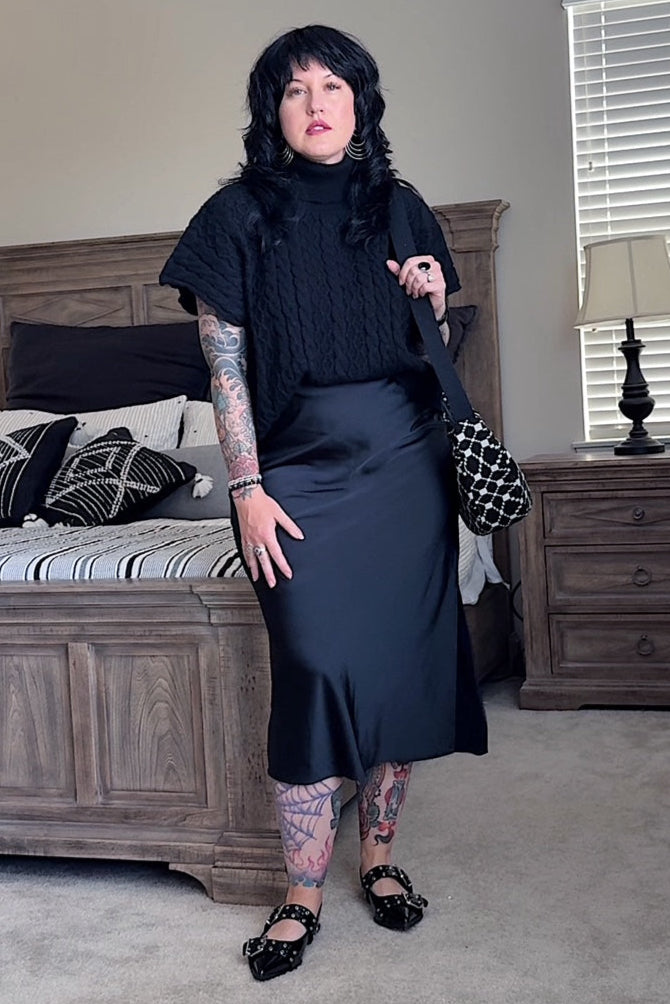 Woman in a black outfit standing in a bedroom