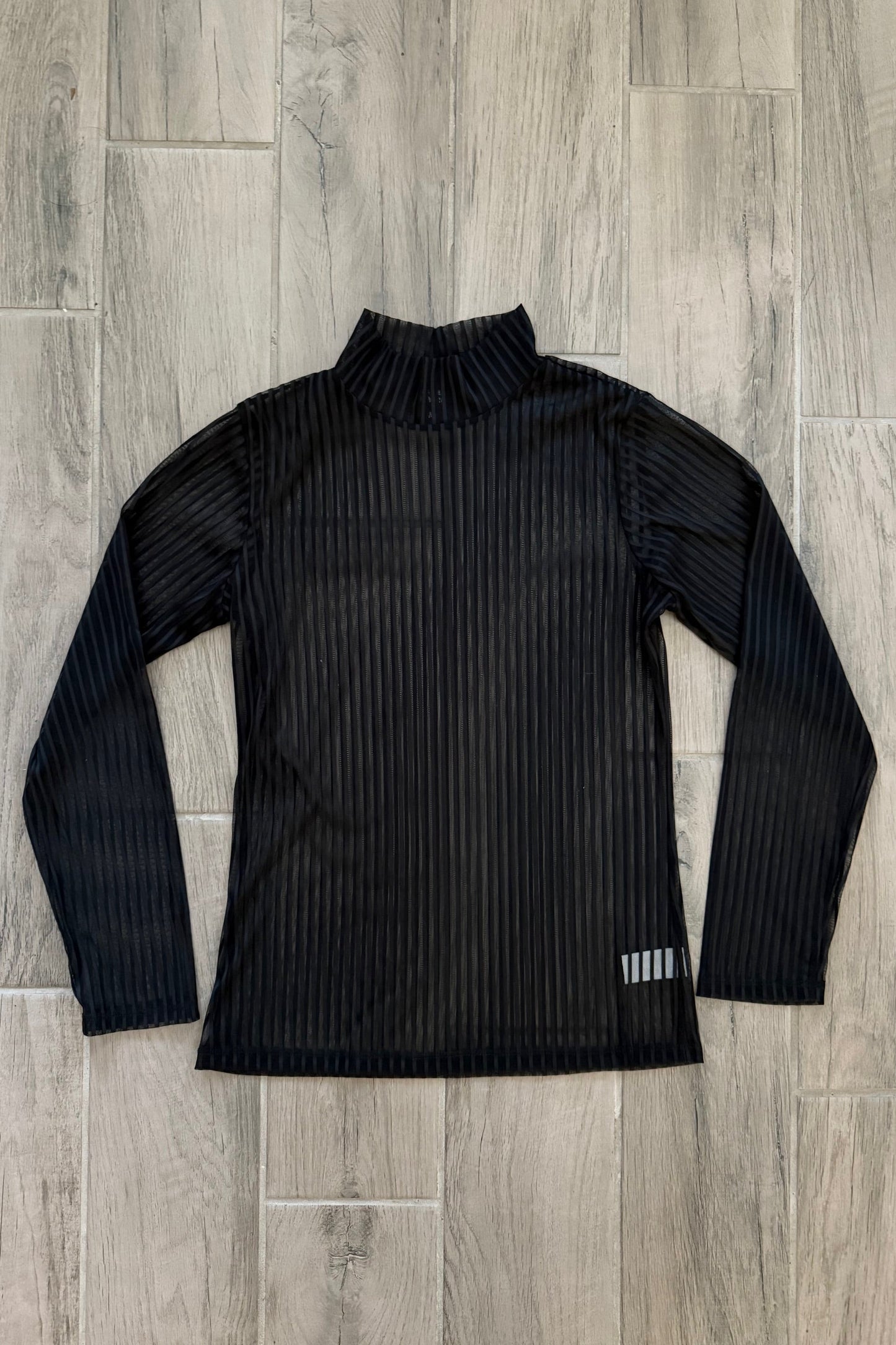 Black ribbed long-sleeve shirt on a wooden floor