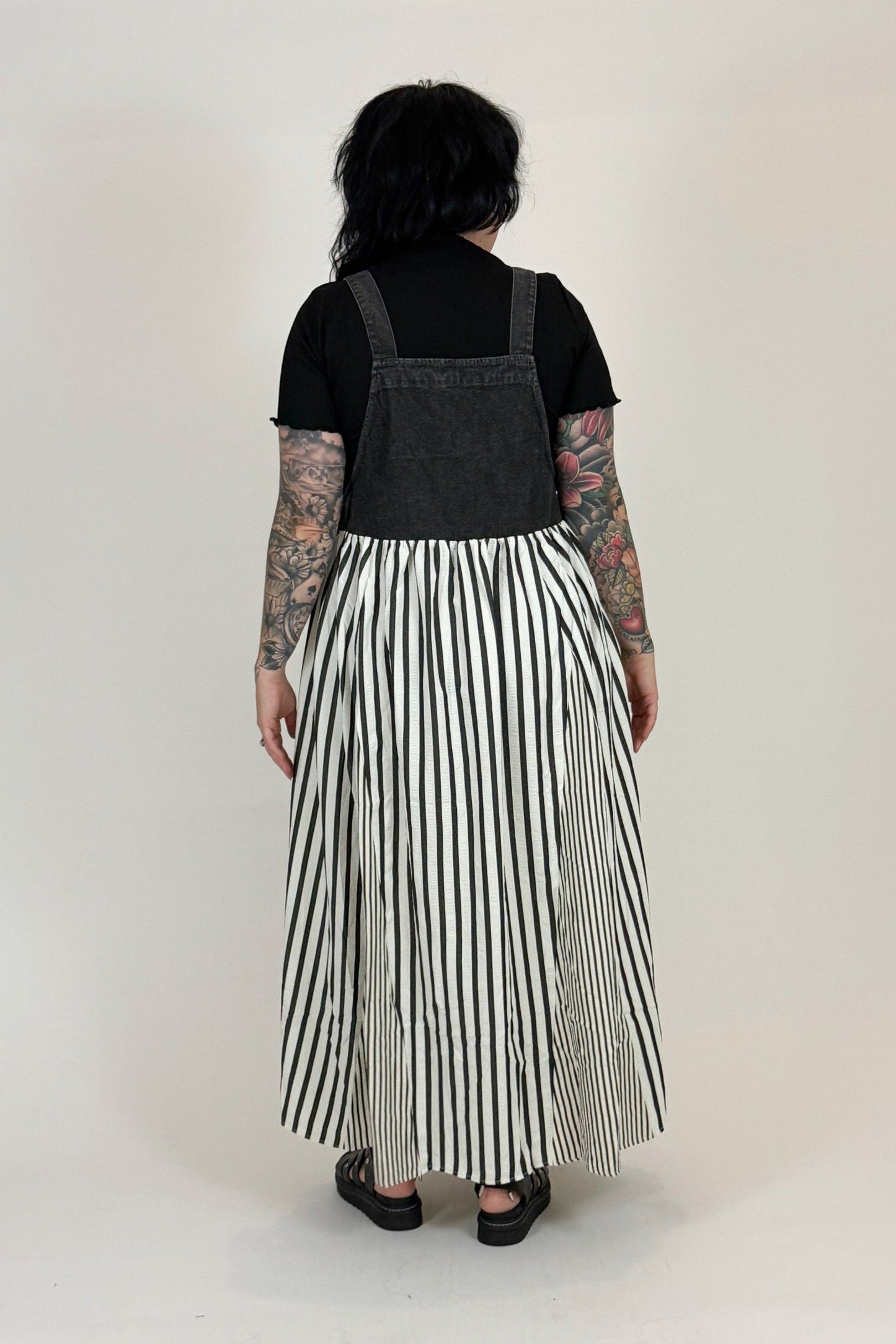 Person wearing a black top and striped skirt against a white background