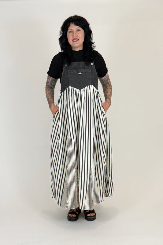 Person wearing a black and gray top with a long black and white striped skirt on a white background
