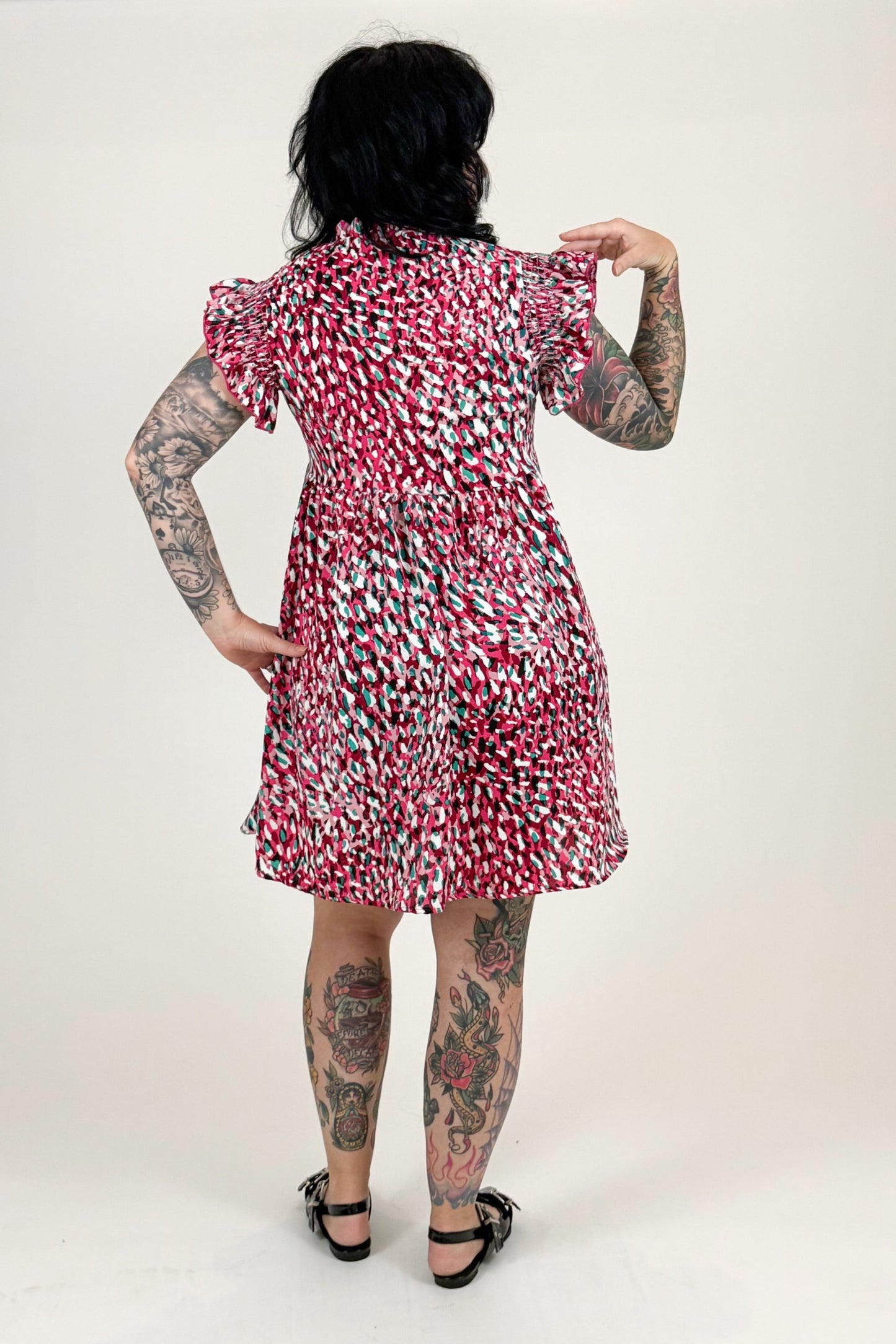 Person wearing a patterned dress standing against a white backdrop