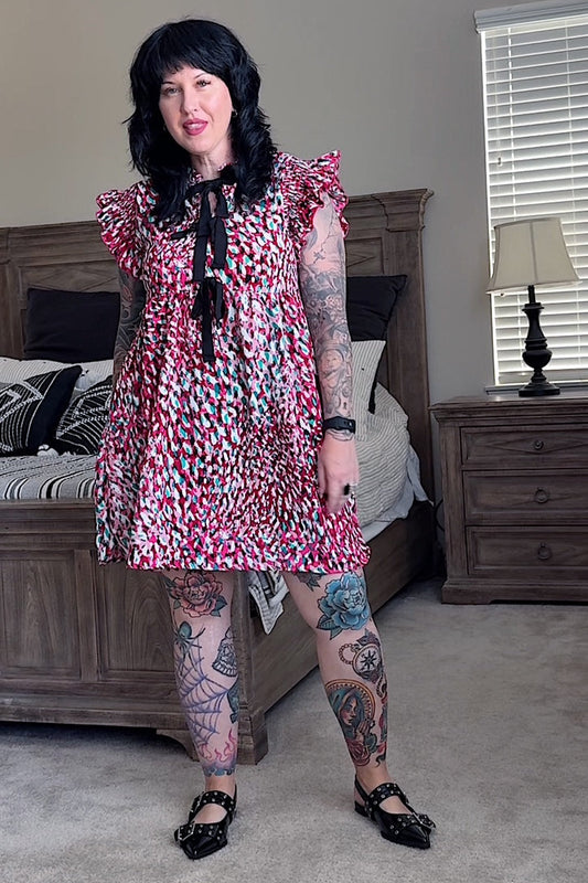 Woman in a leopard dress standing in a bedroom