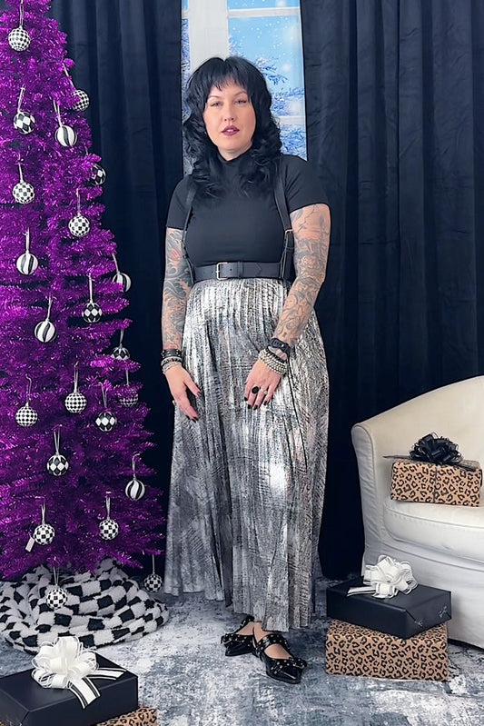 Person standing in a festive room with a purple Christmas tree and gift boxes.