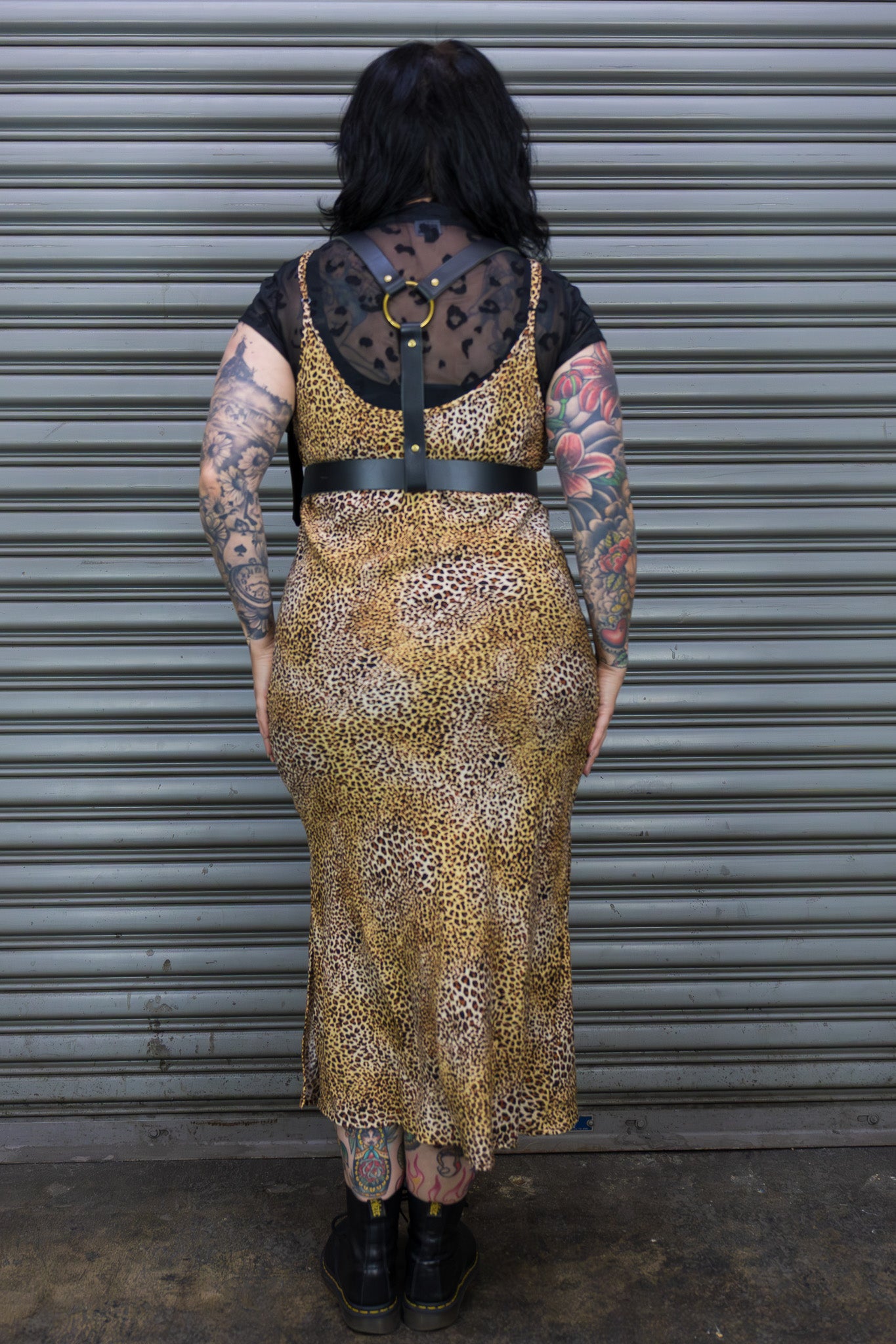 Person wearing a leopard print dress with a black belt against a metal shutter background