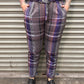 Person wearing plaid pants standing in front of a metal shutter.