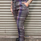 Person wearing plaid pants standing against a metal shutter.