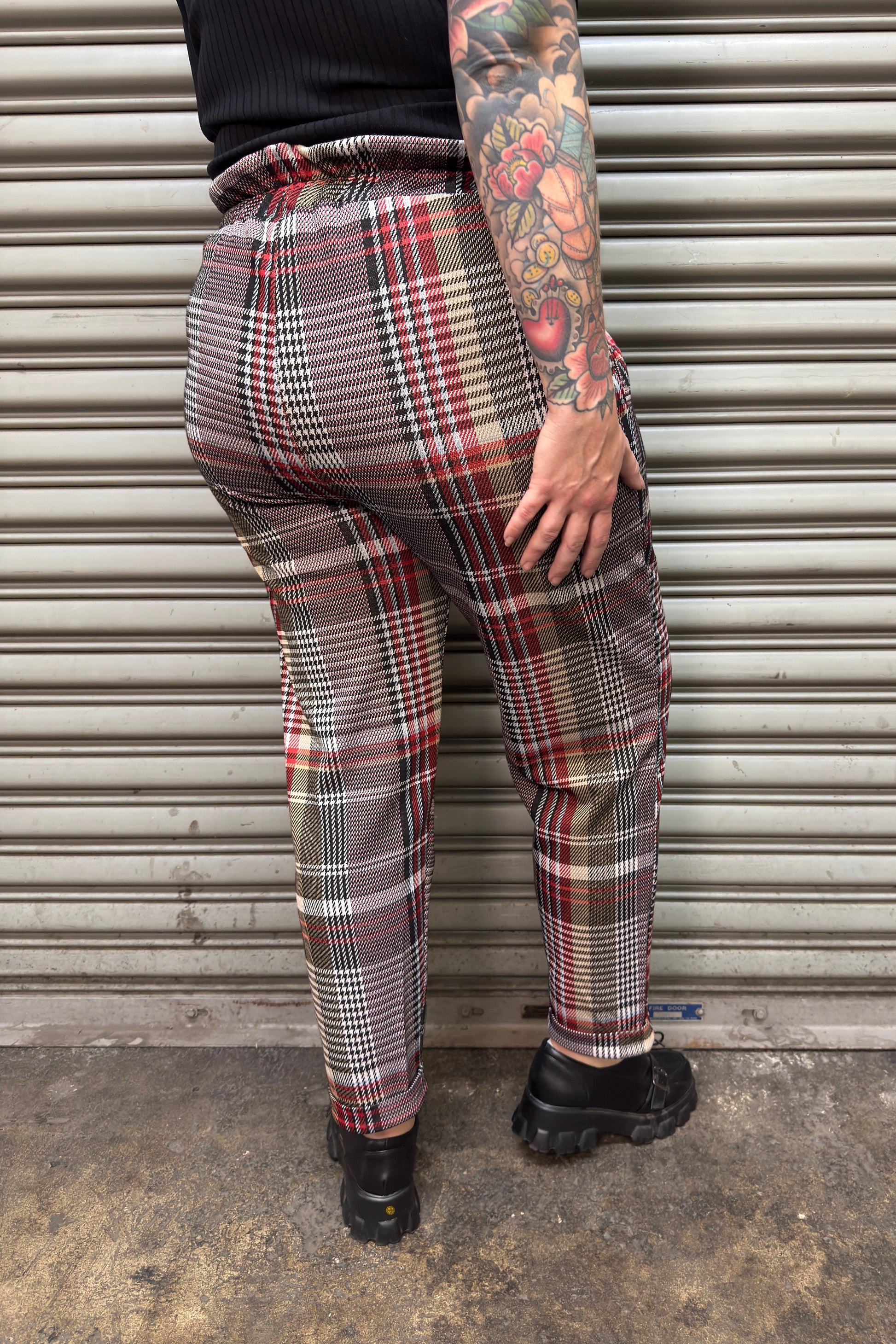 Person wearing plaid pants standing in front of a metal shutter.