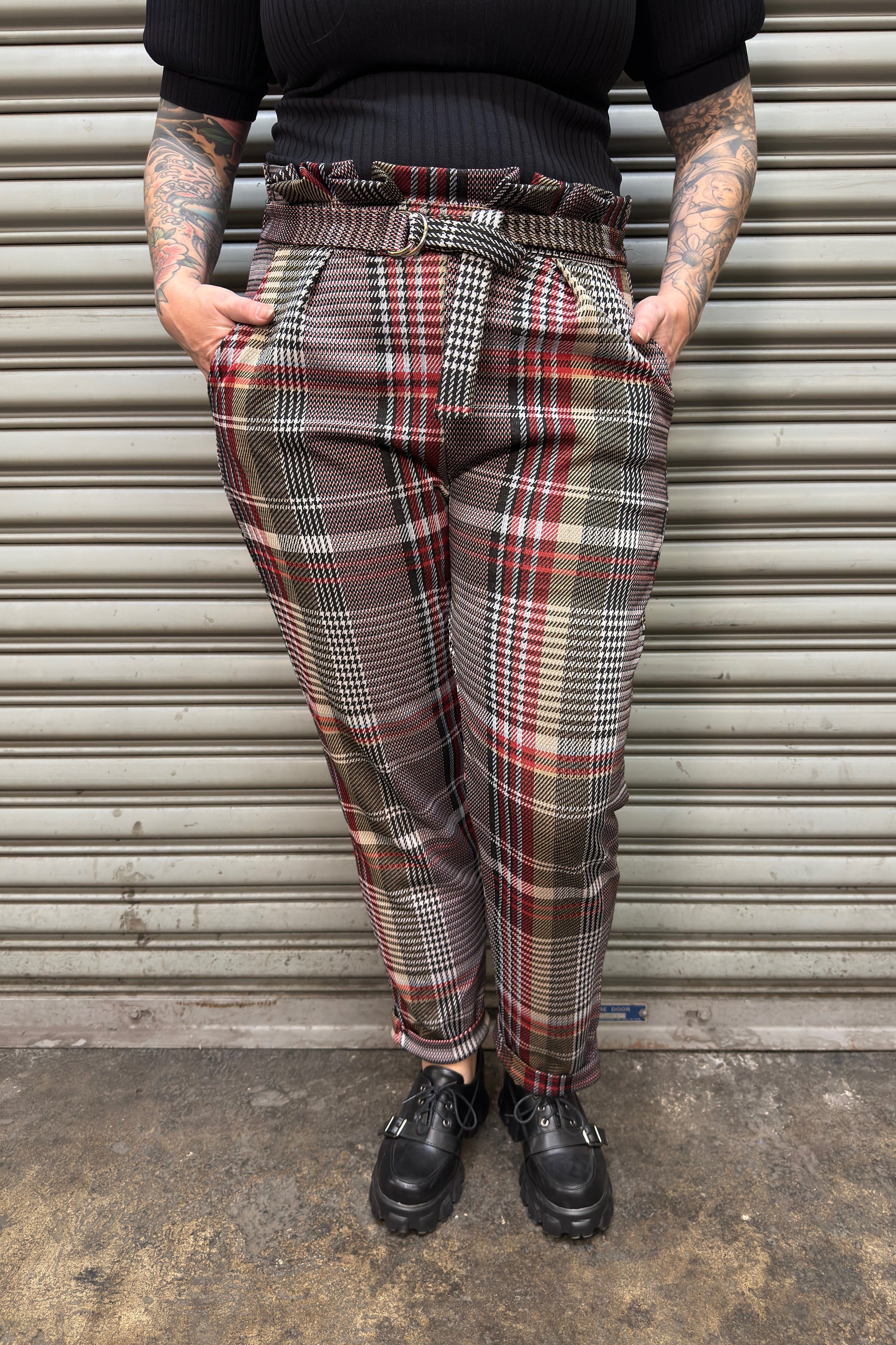 Person wearing plaid pants standing in front of a metal shutter.