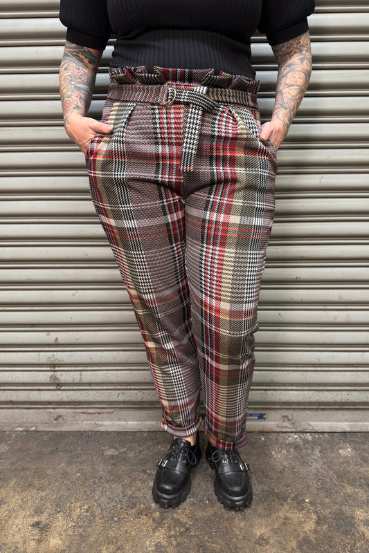 Person wearing plaid pants standing in front of a metal shutter.