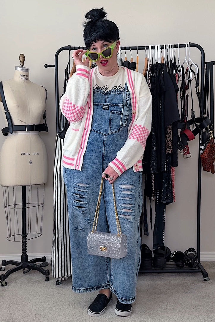 Person wearing a checkered jacket, denim overalls, and sunglasses in a clothing store.