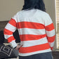 Person wearing a red and white striped sweater and dark skirt in a living room.