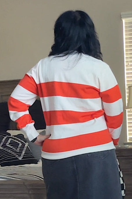 Person wearing a red and white striped sweater and dark skirt in a living room.
