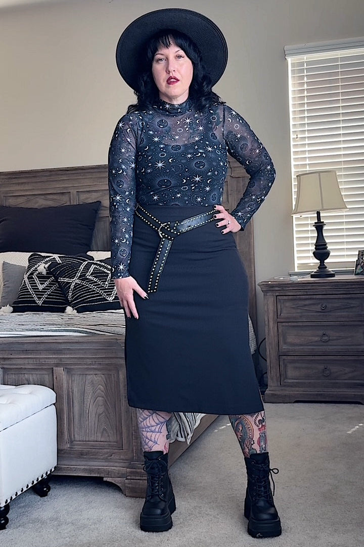 Person wearing a dark outfit with a hat in a living room setting