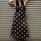 Person wearing a black polka dot dress standing against a metal shutter.