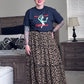 Person wearing a graphic t-shirt and leopard print skirt in a bedroom setting