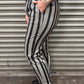 Person wearing black and white striped pants with tattoos visible, standing against a metallic shutter.