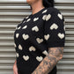 Woman wearing a black sweater with white heart patterns against a metallic shutter background