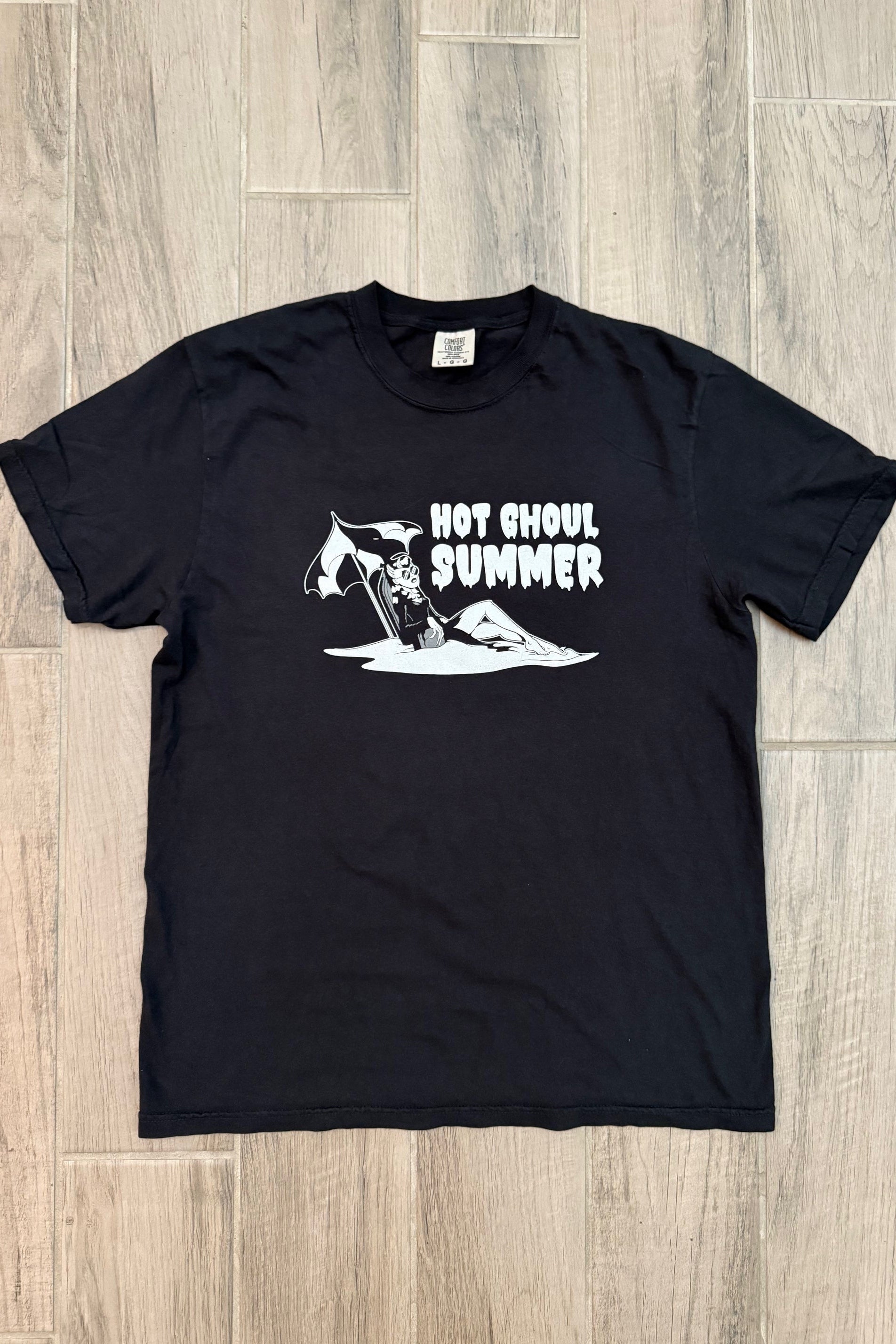 Black t-shirt with white graphic design on a wooden floor