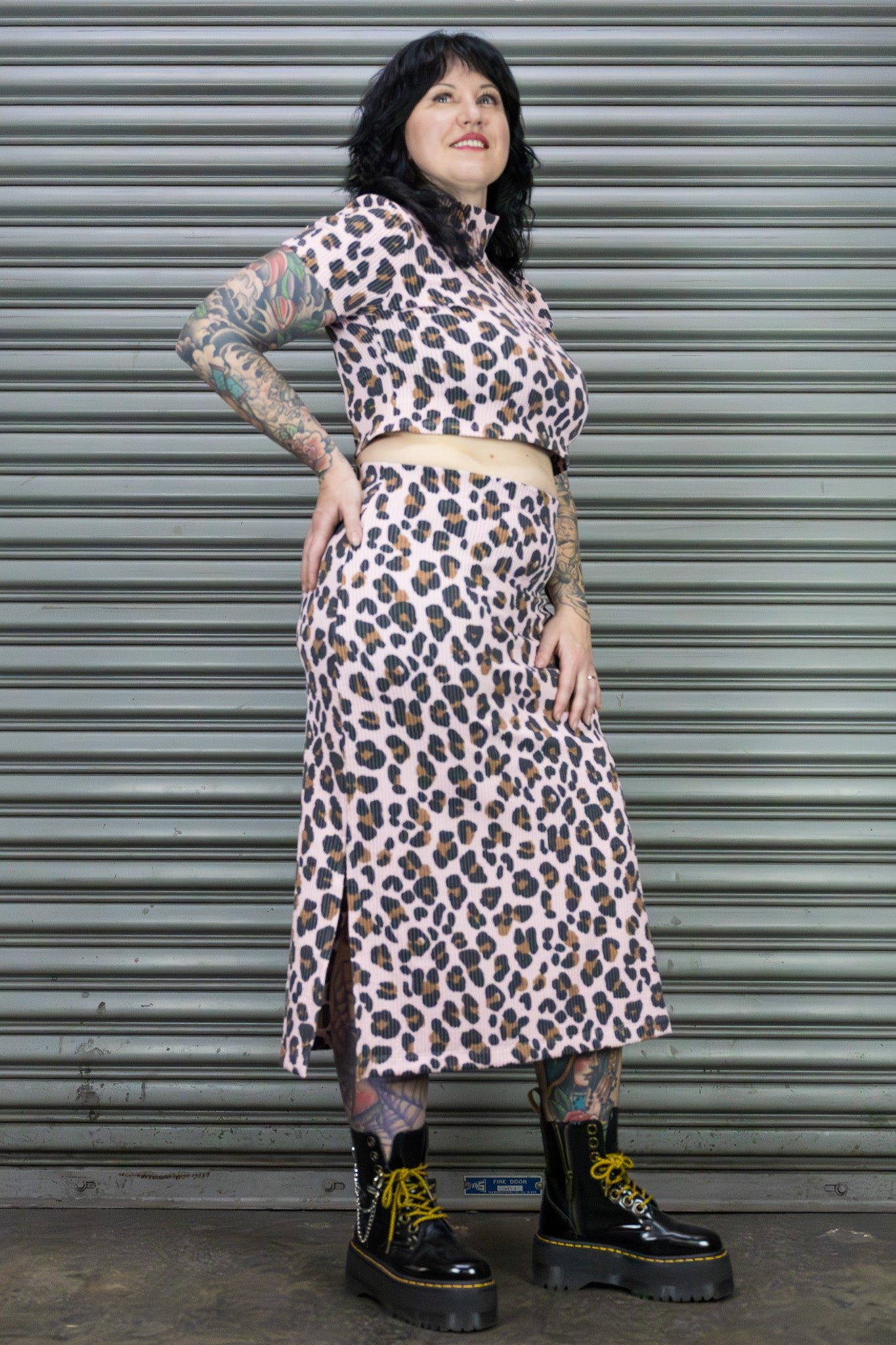 Person wearing a leopard print outfit standing in front of a metal shutter.
