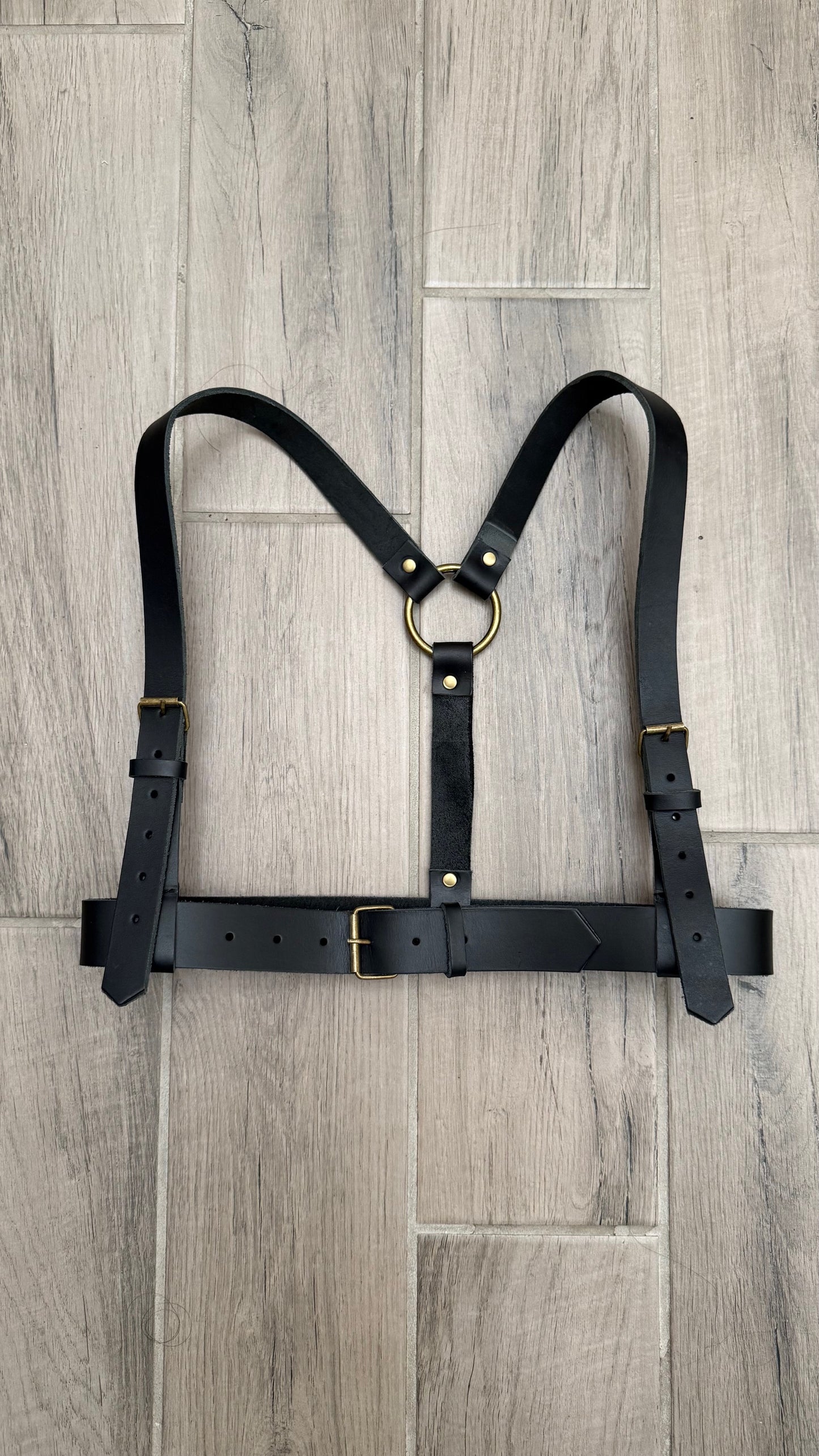 Black leather harness on a wooden floor