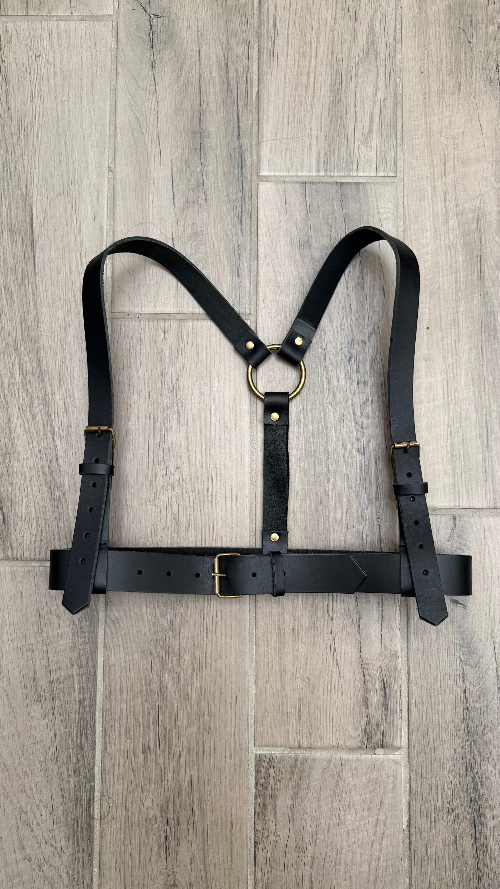 Black leather harness on a wooden floor