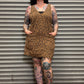 Person wearing a leopard print dress standing in front of a metal shutter.