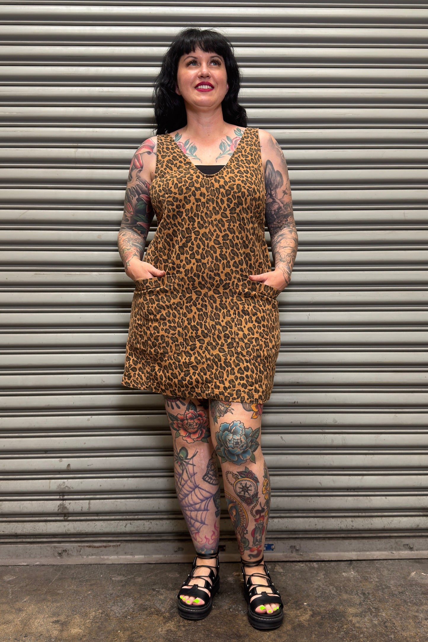 Person wearing a leopard print dress standing in front of a metal shutter.