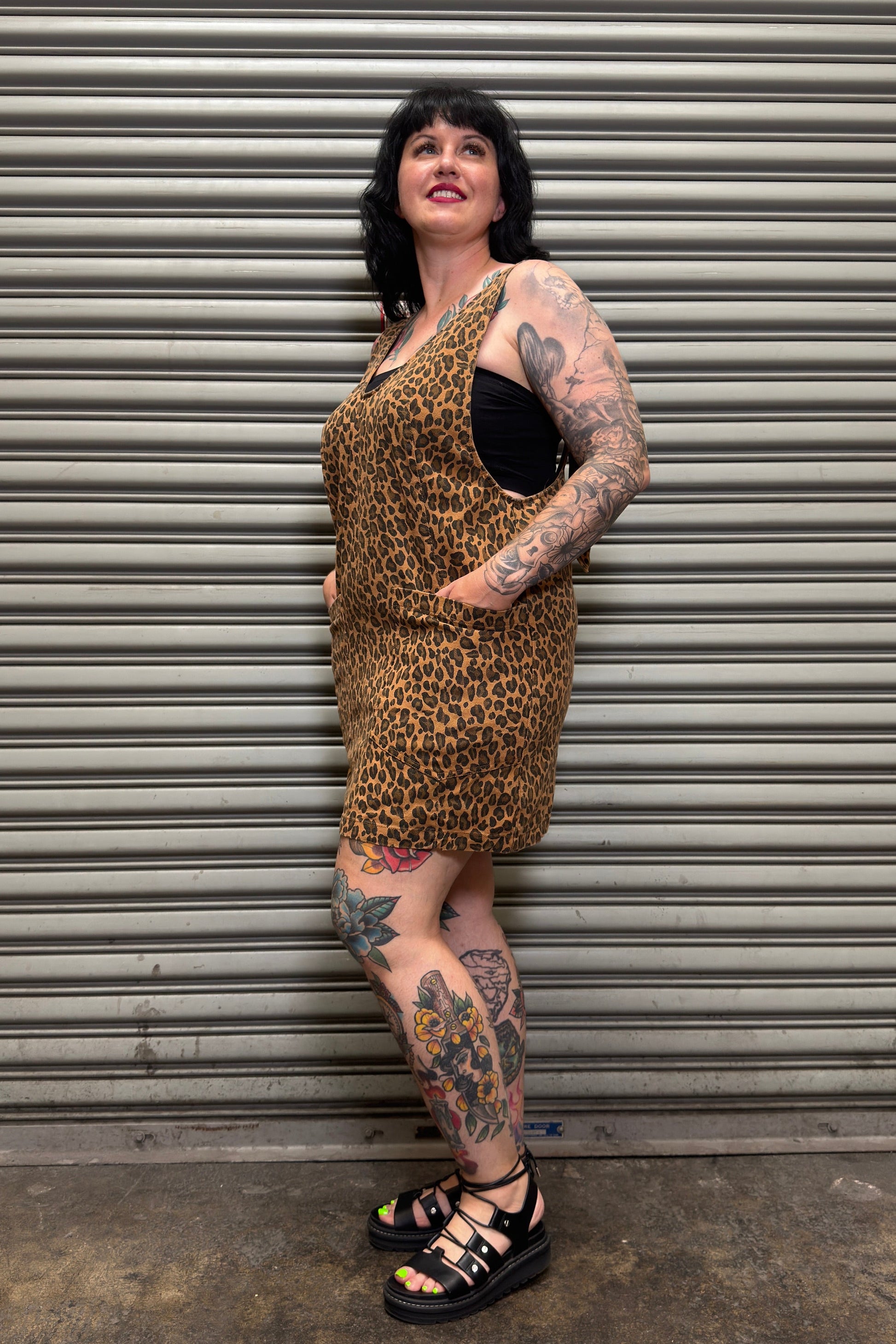Person wearing a leopard print dress standing in front of a metal shutter.