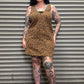 Person wearing a leopard print dress standing in front of a metal shutter.