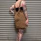 Person wearing a leopard print dress with black overalls against a metal shutter background