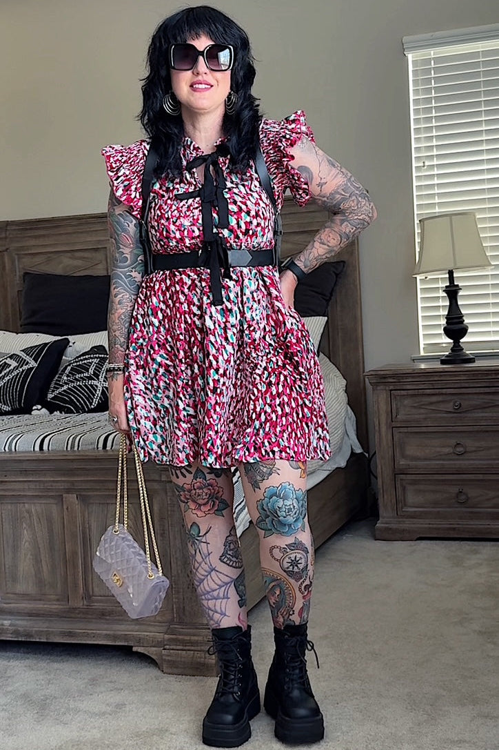 Person wearing a floral dress with suspenders in a bedroom setting
