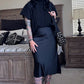 Woman in a black outfit standing in a bedroom