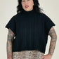 Woman wearing a black turtleneck sweater and leopard print pants on a plain background