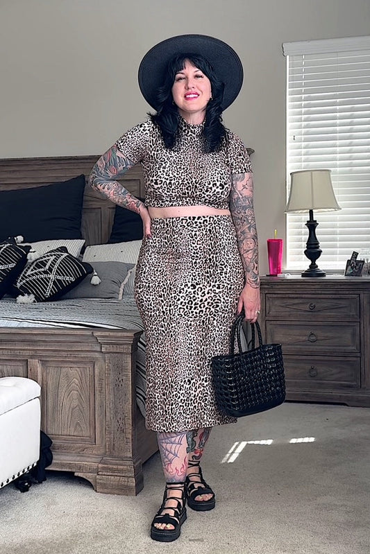 Women standing in bedroom wearing fitted rib knit leopard print pencil skirt matching top, sandals, hot, and holding a purse