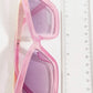 Pink sunglasses with gradient lenses next to a ruler on a white background