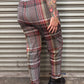 Person wearing plaid pants standing in front of a metal shutter.