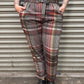 Person wearing plaid pants standing in front of a metal shutter.