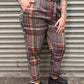 Person wearing plaid pants and black shoes standing in front of a metallic shutter.