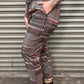 Person wearing plaid pants and black shoes standing against a metallic shutter.