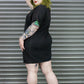 Person wearing a black t-shirt with tattoos standing in front of a metal shutter.