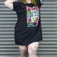 Person wearing a black t-shirt with colorful graphic design in front of a metallic shutter.
