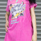 Person wearing a pink graphic t-shirt with text and graphics against a metallic background