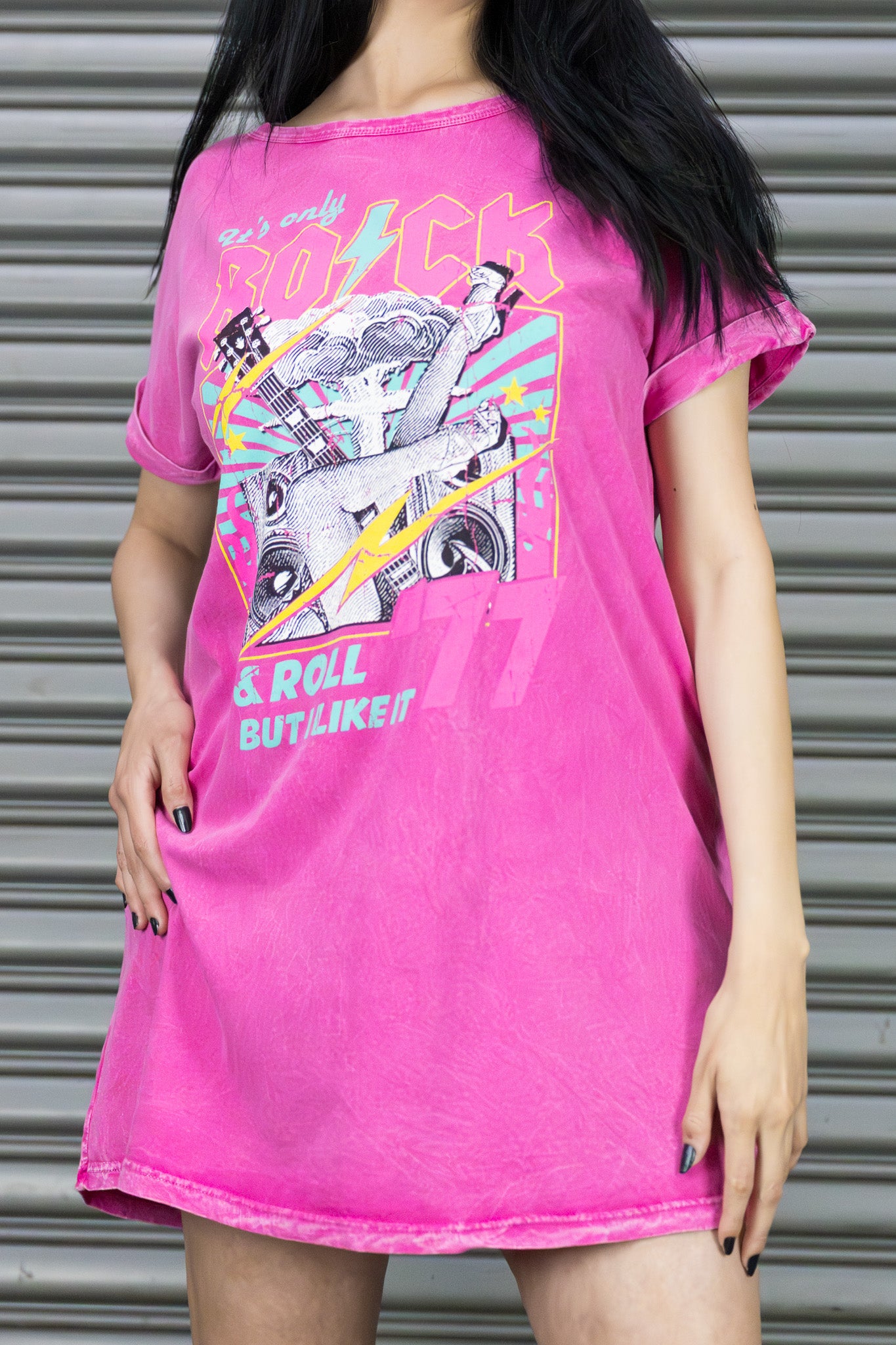 Person wearing a pink graphic t-shirt with text and graphics against a metallic background