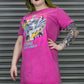Person wearing a bright pink t-shirt with graphic design and text, standing against a metallic shutter background.
