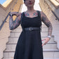 woman with tattoos on stairs in black dress and leather fashion harness