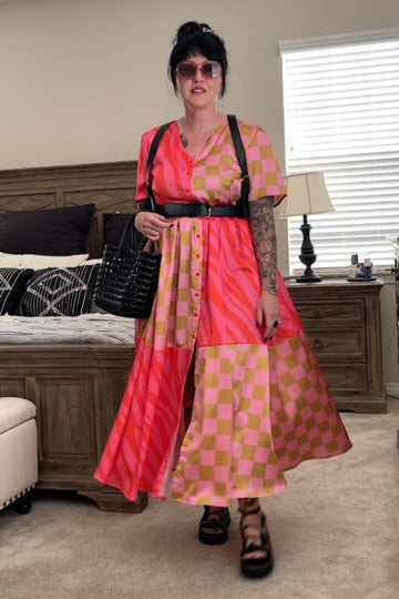 Person wearing a pink and gold checkered dress in a bedroom setting