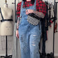 Person wearing a red plaid shirt, blue denim overalls, and black boots in a clothing store.