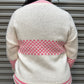 Person wearing a cream sweater with pink patterns against a metallic shutter background