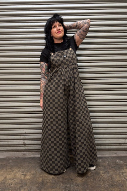 Person wearing a checkered dress standing in front of a metal shutter.