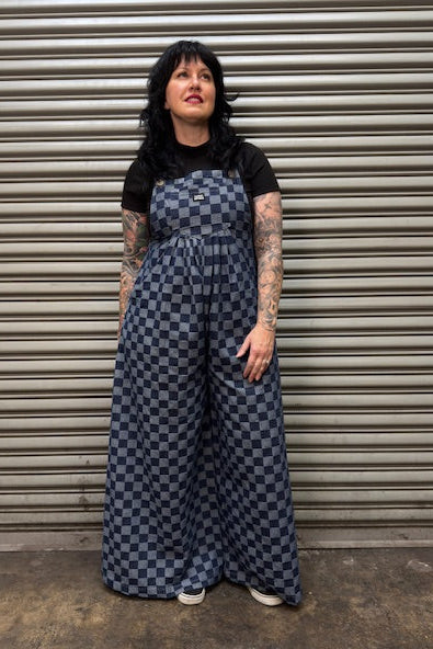 Person wearing a blue checkered dress standing in front of a metal shutter.